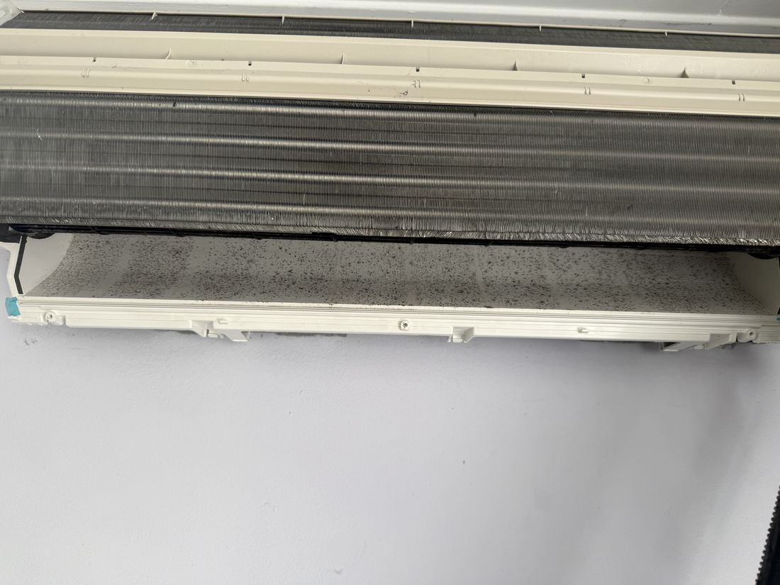 Binnenunit met zichtbare zwarte aanslag op de bak onder de warmtewisselaar